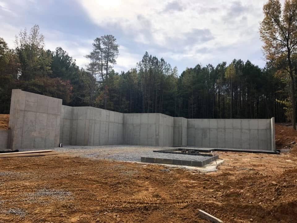 Long poured concrete retaining wall with pine backdrop